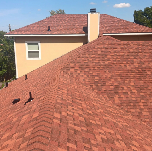 Full multi-gable roof replacement with reddish-brown terracotta architectural shingles on beige walls with white chimney in Harker Heights TX by Martinez Construction